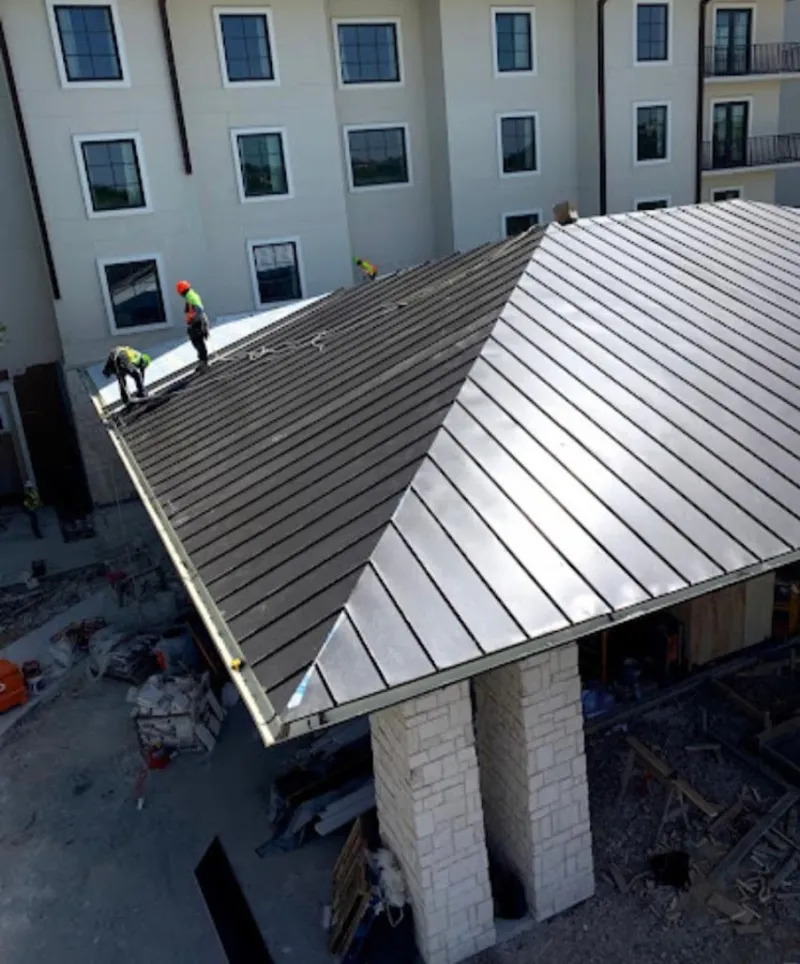 Crew installing standing seam metal roof panels on a commercial project in Lake Dallas